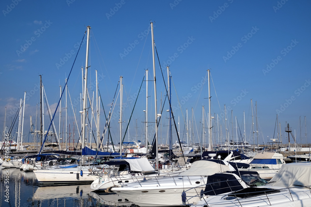 Sea yachts dense parking in calm marina water on bright summer day with mountains af far