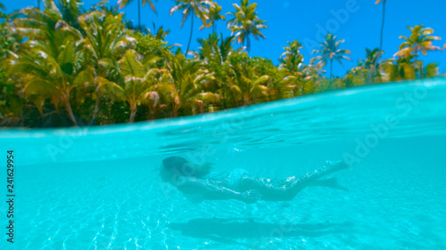 HALF HALF: Young woman swimming underwater during vacation on exotic island.