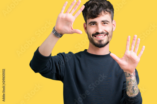 Young handsome man over isolated background Smiling doing frame using hands palms and fingers, camera perspective