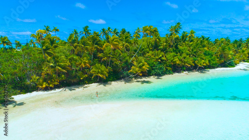 DRONE: Tourist girl in bikini walks into the shallow turquoise ocean water.