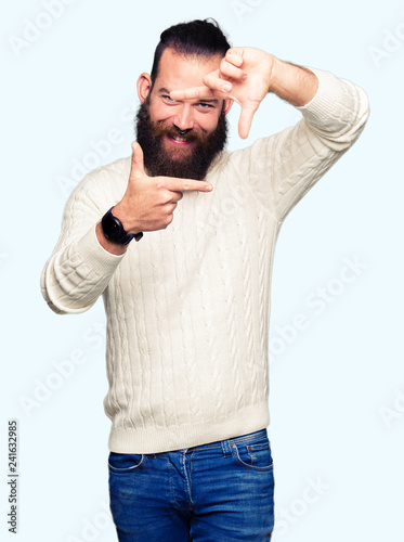 Young hipster man wearing winter sweater smiling making frame with hands and fingers with happy face. Creativity and photography concept.