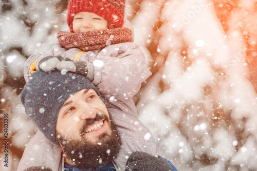 happy father and baby son having fun under sunny winter snow, holiday season.