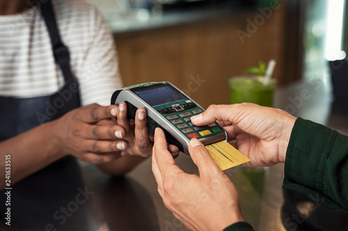 Midsection of female owner taking credit card payment from customer at bar counter in cafeteria photo