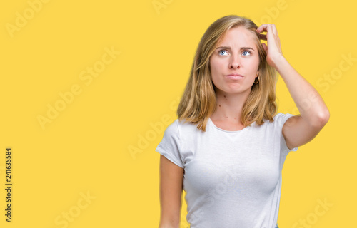 Beautiful young woman wearing casual white t-shirt over isolated background confuse and wonder about question. Uncertain with doubt, thinking with hand on head. Pensive concept.