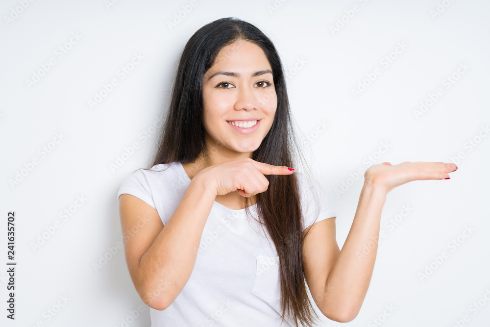 Beautiful brunette woman over isolated background amazed and smiling to the camera while presenting with hand and pointing with finger. Beautiful brunette woman over isolated background amazed and smiling to the camera while presenting with hand and pointing with finger.
