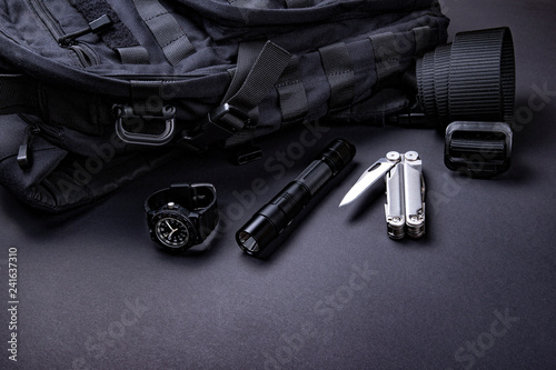Everyday carry (EDC) items for men in black color - backpack, tactical belt, flashlight,  watch and silver multi tool.  photo