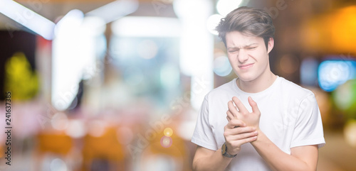 Young handsome man wearing casual white t-shirt over isolated background Suffering pain on hands and fingers, arthritis inflammation