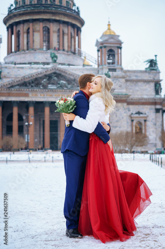 beautiful woman in red dress and man posing standing in winter, wedding in St. Petersburg. © Екатерина Переславце