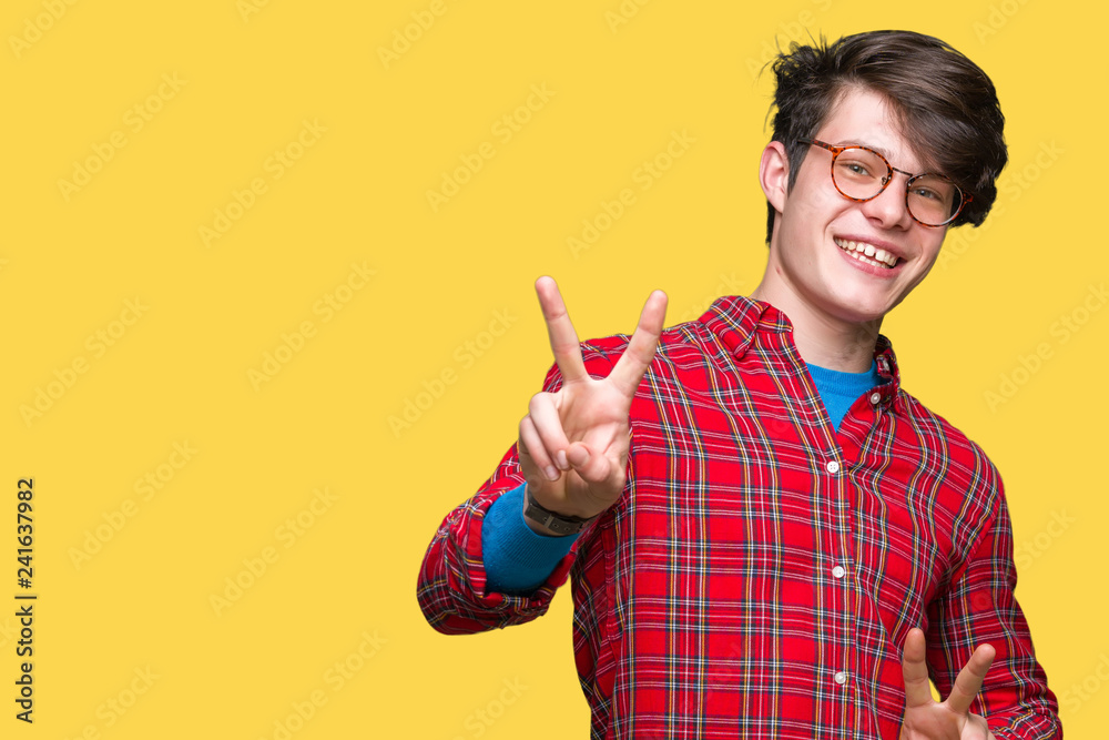 Young handsome man wearing glasses over isolated background smiling looking to the camera showing fingers doing victory sign. Number two. Young handsome man wearing glasses over isolated background smiling looking to the camera showing fingers doing victory sign. Number two.