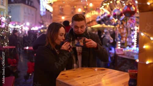 Happy young Couple drink Hot Wine on Christmas Fair Street at Night