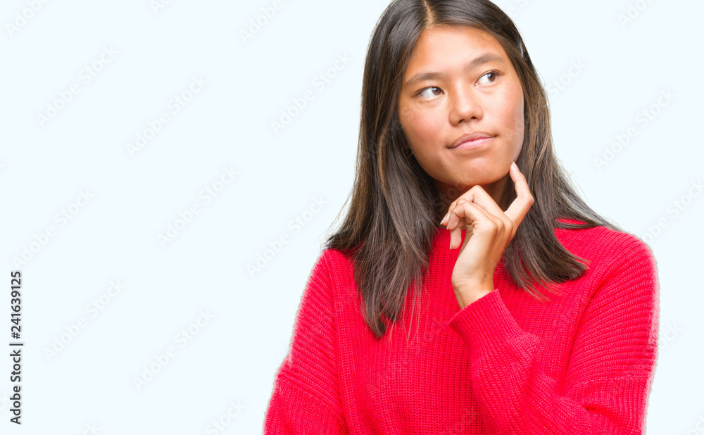 Young asian woman wearing winter sweater over isolated background with hand on chin thinking about question, pensive expression. Smiling with thoughtful face. Doubt concept. Young asian woman wearing winter sweater over isolated background with hand on chin thinking about question, pensive expression. Smiling with thoughtful face. Doubt concept.