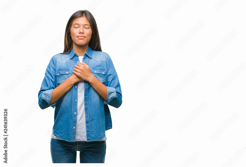 Young asian woman over isolated background smiling with hands on chest with closed eyes and grateful gesture on face. Health concept. Young asian woman over isolated background smiling with hands on chest with closed eyes and grateful gesture on face. Health concept.