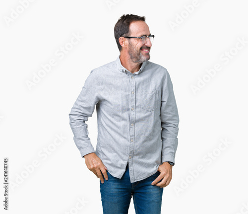 Handsome middle age elegant senior man wearing glasses over isolated background looking away to side with smile on face, natural expression. Laughing confident.