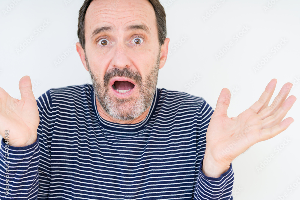 Handsome senior man over isolated background clueless and confused expression with arms and hands raised. Doubt concept. Handsome senior man over isolated background clueless and confused expression with arms and hands raised. Doubt concept.