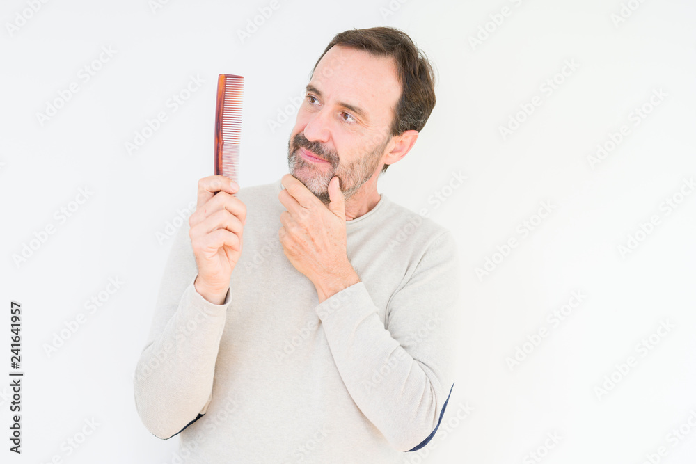 Senior man holding hair comb over isolated background serious face thinking about question, very confused idea Senior man holding hair comb over isolated background serious face thinking about question, very confused idea