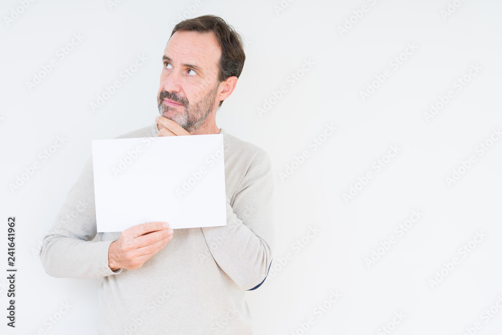 Senior man holding blank paper sheet over isolated background serious face thinking about question, very confused idea Senior man holding blank paper sheet over isolated background serious face thinking about question, very confused idea