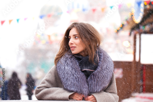 Young brunette woman in a gray coat with a fur collar
