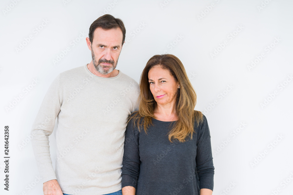 Beautiful middle age couple in love over isolated background skeptic and nervous, frowning upset because of problem. Negative person.