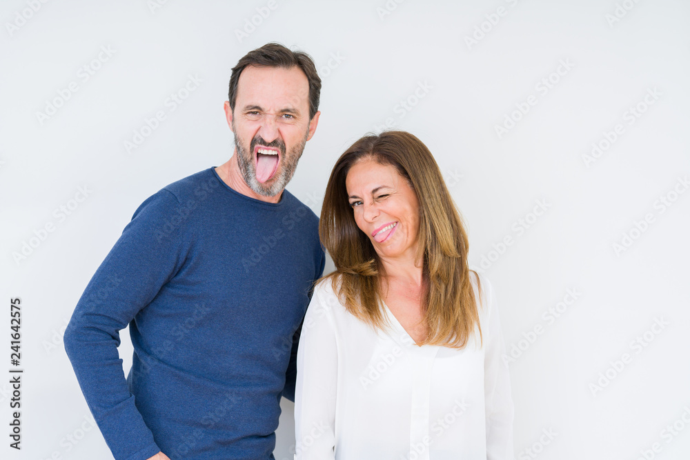 Beautiful middle age couple in love over isolated background sticking tongue out happy with funny expression. Emotion concept.