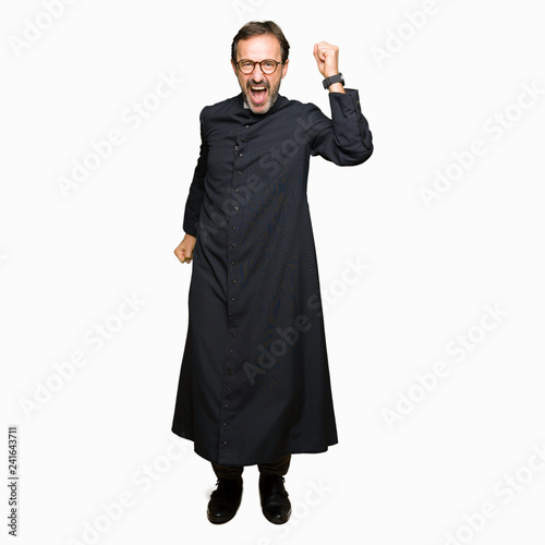 Middle age priest man wearing catholic robe Dancing happy and cheerful, smiling moving casual and confident listening to music