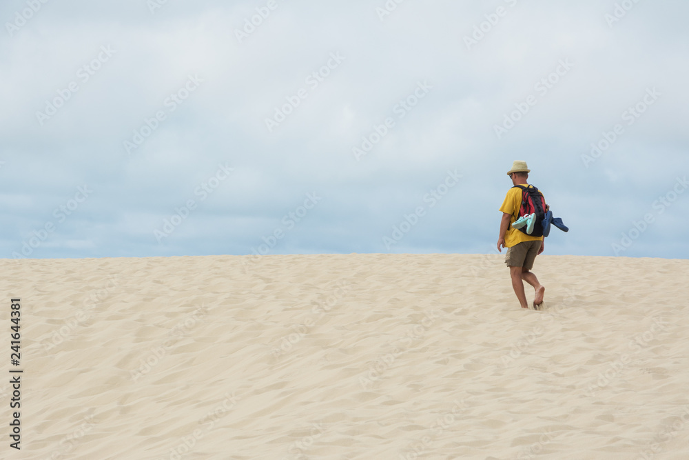 young man with backpack going in the sandy desert young man with backpack going in the sandy desert