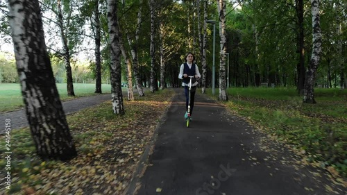Girl from school ride a scooter in park in autumn.