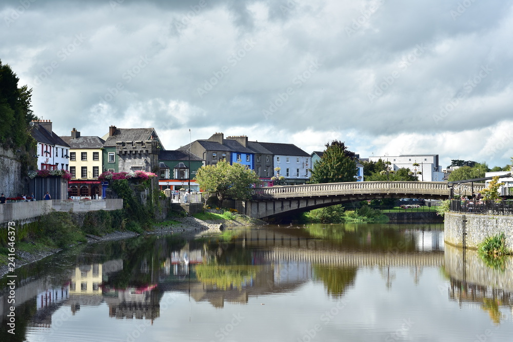 Calm river Nore reflecting historical buildings in Kilkenny on its surface.