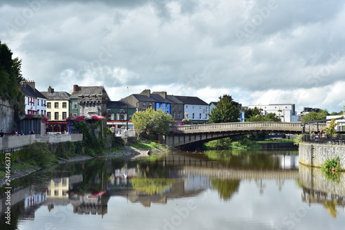 Calm river Nore reflecting historical buildings in Kilkenny on its surface.