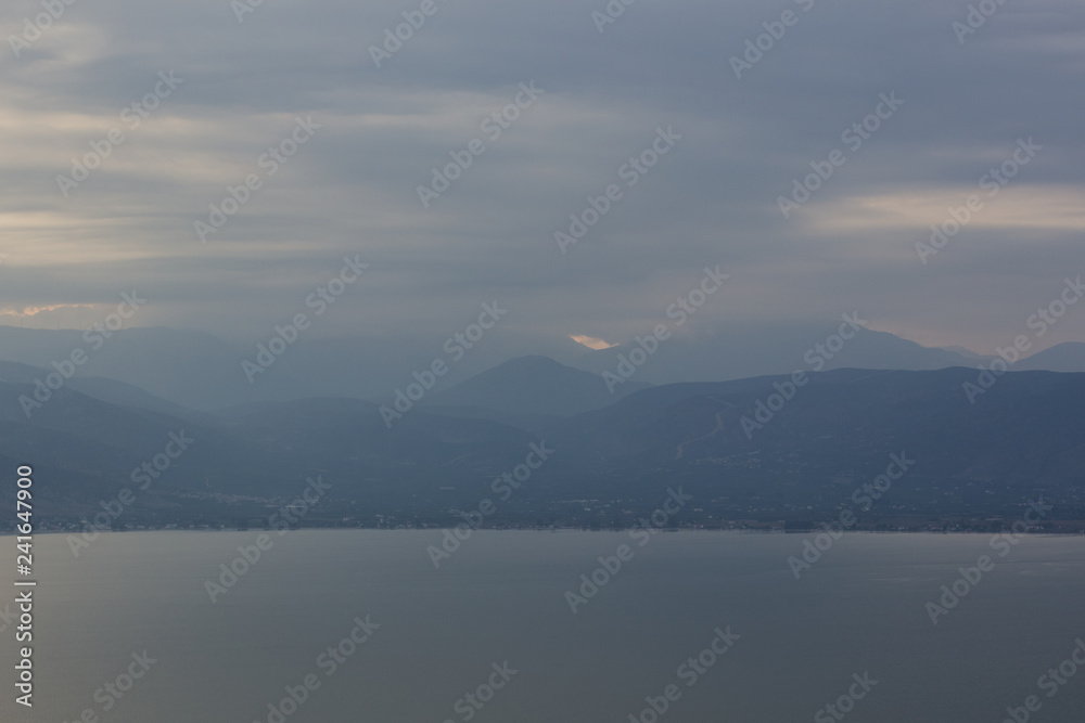 abstract unfocused nature wallpaper background landscape of cloudy and foggy big lake and mountain horizon silhouettes scenery view 