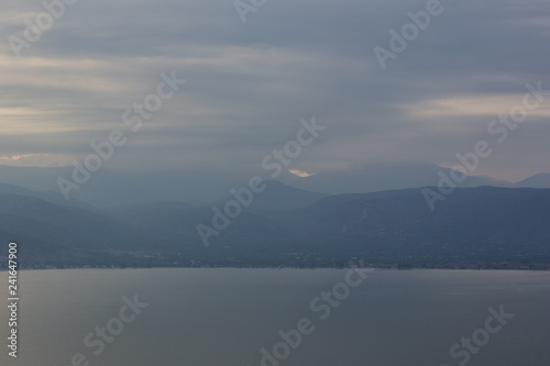 abstract unfocused nature wallpaper background landscape of cloudy and foggy big lake and mountain horizon silhouettes scenery view 