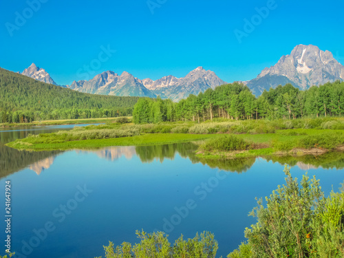 Grand Teton National Park, Wyoming, United States. Scenic landscape of Teton Range of the Rocky Mountains reflecting in the calm waters of Jackson Lake. North America in summer blue sky, copy space.