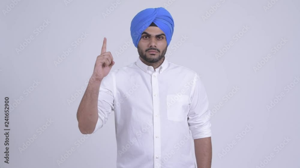 Young bearded Indian Sikh man pointing up Young bearded Indian Sikh man pointing up