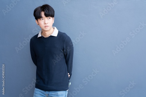 Portrait of Young Asian teenage cool hair stylish wearing blue sweater indicate blank space on blue navy wall background.