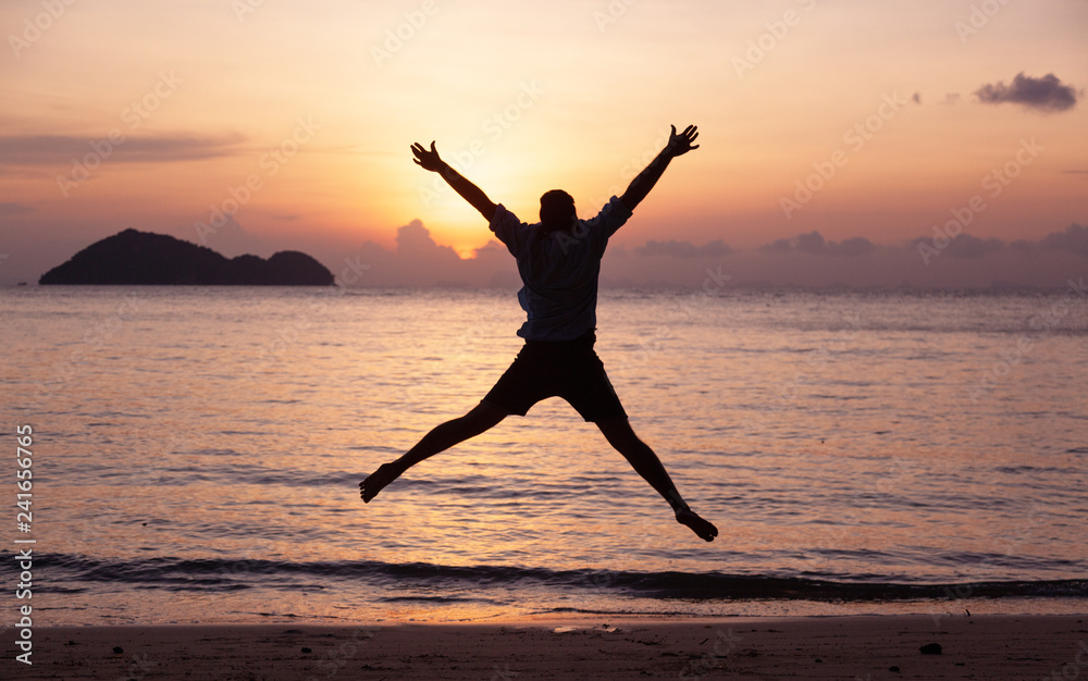 Silhouette of a jumping man on the seashore at sunset, man and nature concept, beauty lifestyle freedom vacation travel