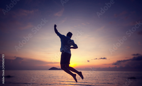 Silhouette of a jumping man on the seashore at sunset  man and nature concept  beauty lifestyle freedom vacation travel