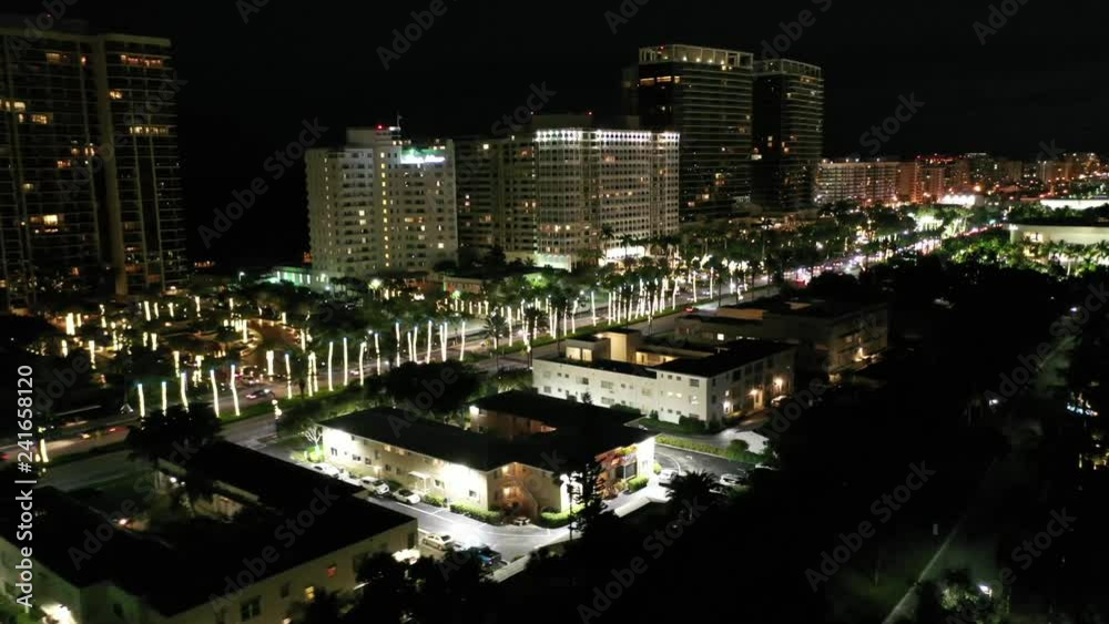Aerial of buildings and sights on the Bal Harbour Beachfront and surrounding area at night. Holiday string lights adorn trees along A1A. Aerial of buildings and sights on the Bal Harbour Beachfront and surrounding area at night. Holiday string lights adorn trees along A1A.