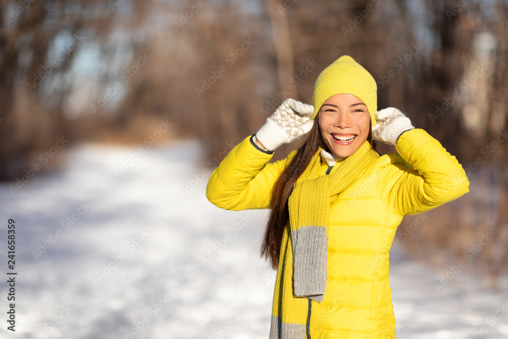 Obraz premium Winter woman smiling emotion outside in nature forest Asian girl happy wearing yellow hat and gloves for cold season. Walk in nature park in snow.