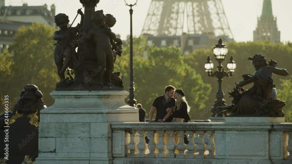 Happy couple kissing near statues on Pont Alexandre / Paris, Ile de France, France