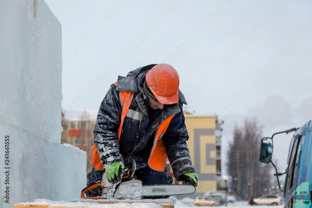 A worker in a helmet inspects a chainsaw chain. A worker in a helmet inspects a chainsaw chain.