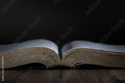 open book on black background  Dramatic light on bible / book. Room for text above or below of book. 
