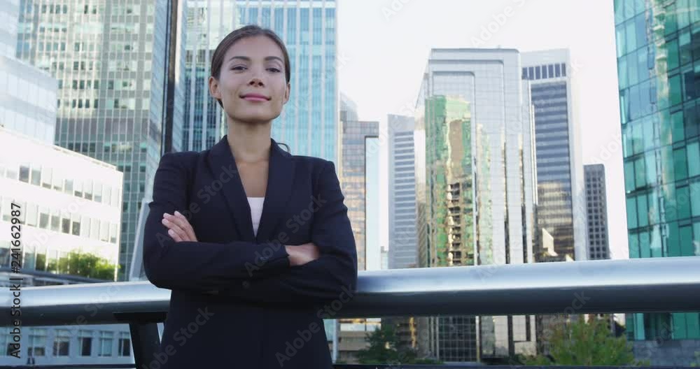 Women in Business concept. Confident young businesswoman standing arms crossed against office buildings. Beautiful female executive is standing in city business center. Women in Business concept. Confident young businesswoman standing arms crossed against office buildings. Beautiful female executive is standing in city business center.