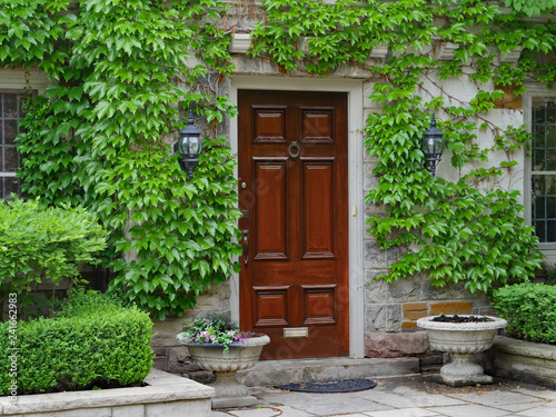 elegant wooden front door of house surrounded by ivy