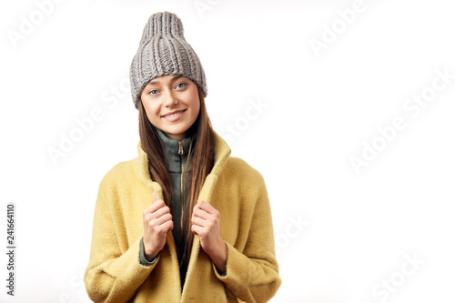 Cheerful attractive woman of european appearance wearing a lovely coat and knitted hat looking at camera with apositive smile, isolated on a white background. Women Fashion and Apparel Concept photo