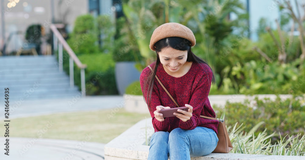 Fototapeta premium Woman use of mobile phone and sit at the park
