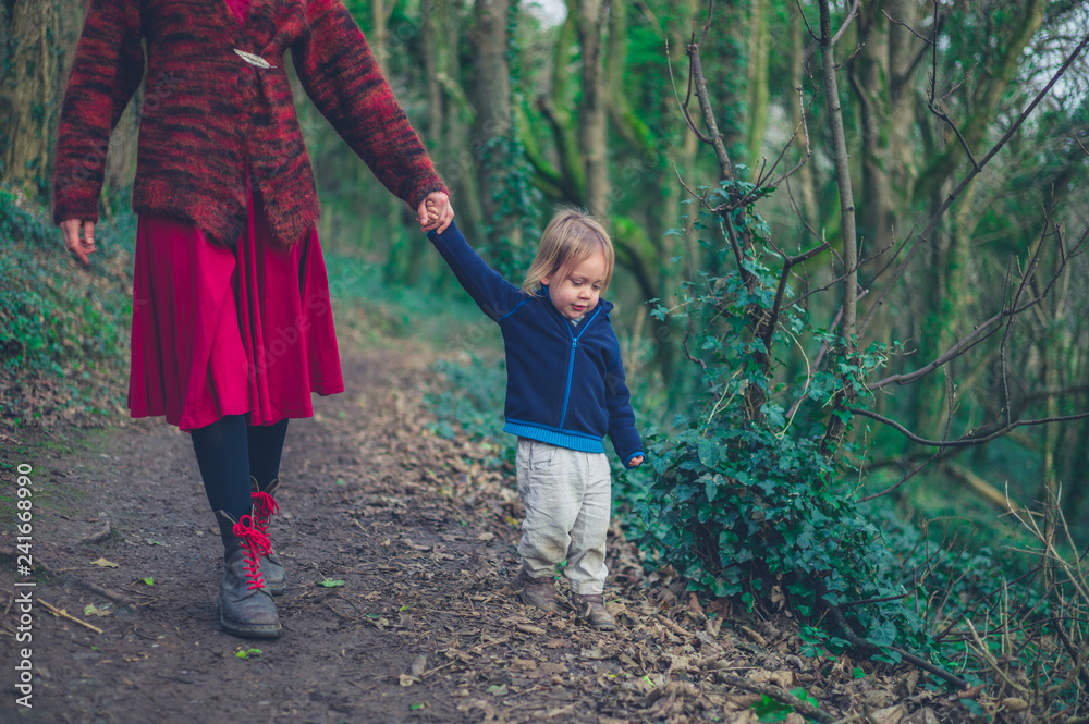 Fototapeta premium Young mother and toddler walking in the woods