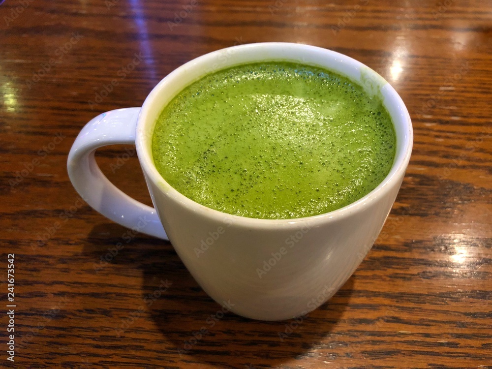 Hot green tea latte on the wood table Hot green tea latte on the wood table