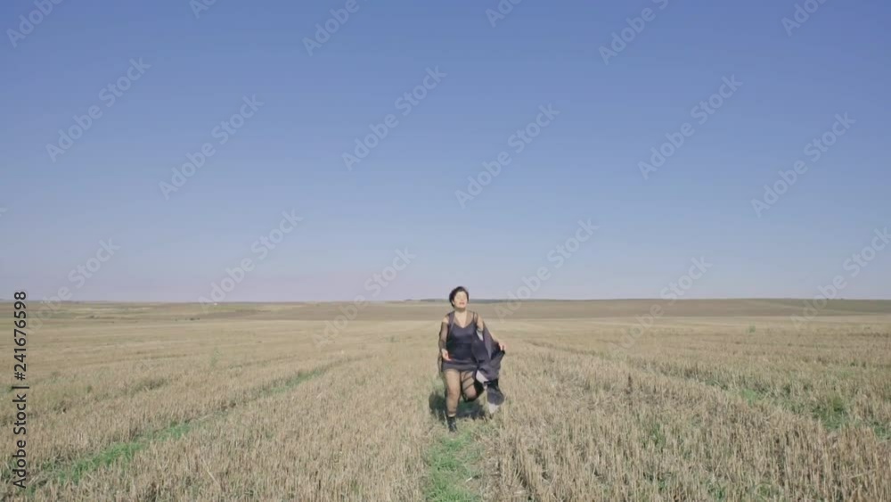 Young woman running through a harvested farm field in a smart trendy outfit approaching and then passing the camera - slow motion. Young woman running through a harvested farm field in a smart trendy outfit approaching and then passing the camera - slow motion.