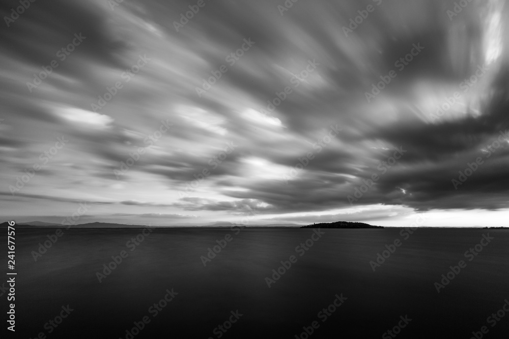 Beautiful long exposure wide angle view of a lake with an huge sky with clouds, above an island