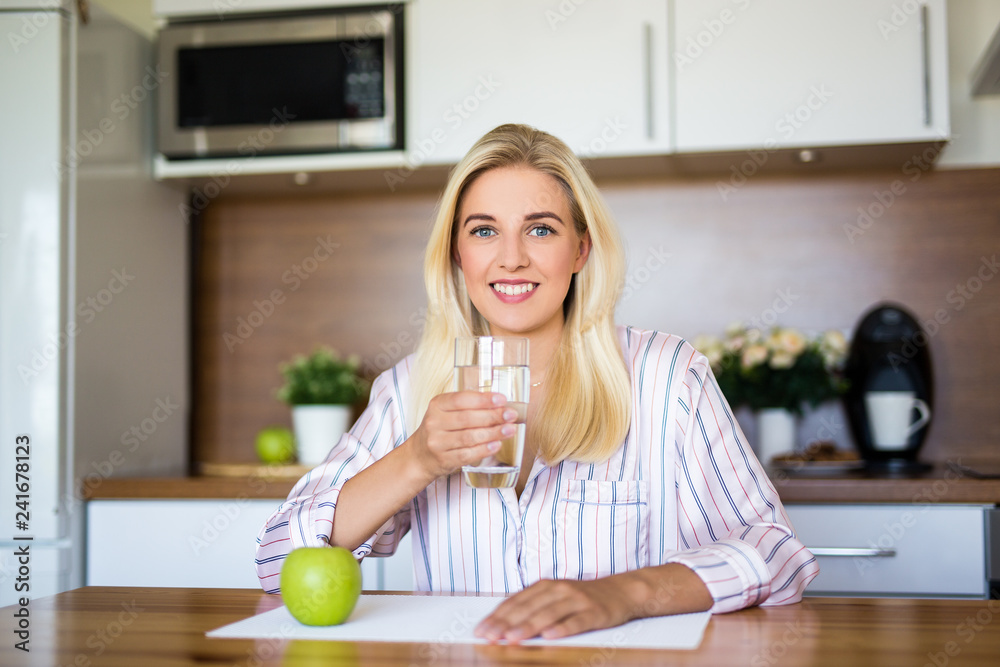 portrait of beautiful girl sitting with apple and glass of water in kitchen portrait of beautiful girl sitting with apple and glass of water in kitchen