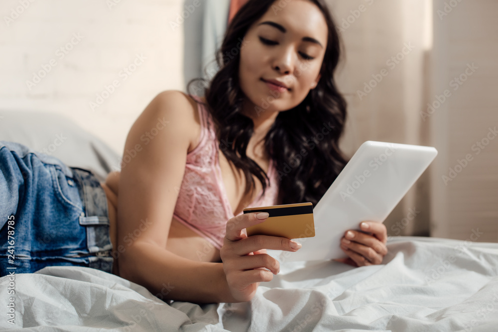 beautiful young asian woman shopping online with digital tablet and credit card in bedroom beautiful young asian woman shopping online with digital tablet and credit card in bedroom